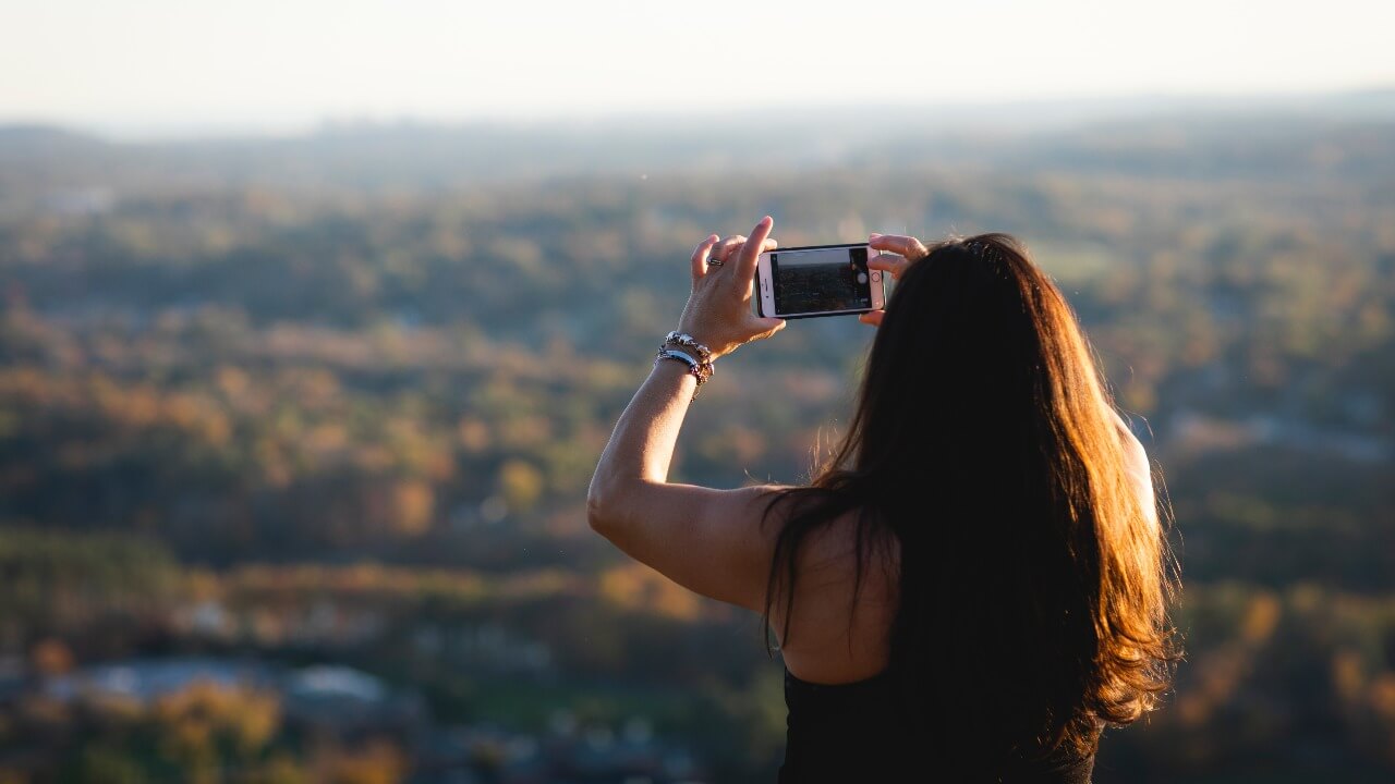 Tami Reilly taking a photo of the Mount Carmel Campus from the top of the Sleeping Giant State Park.